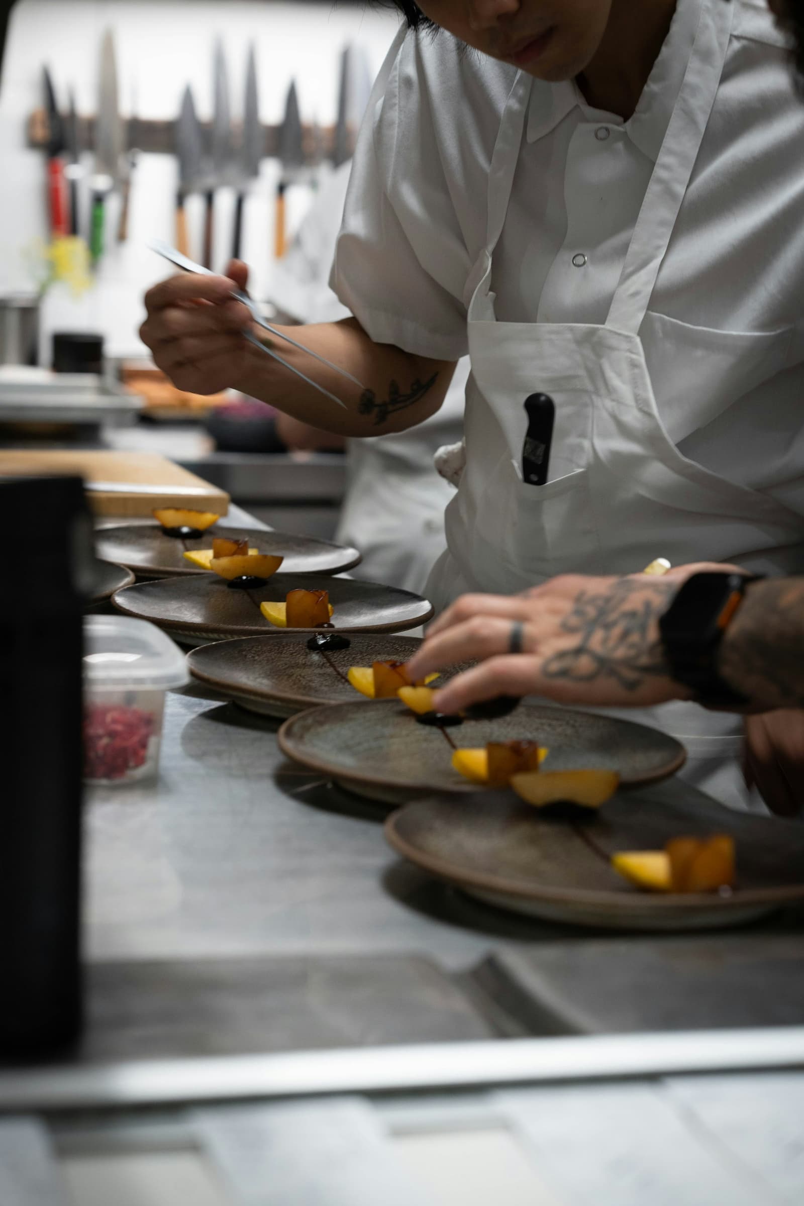 A chef plating a row of dishes on the pass